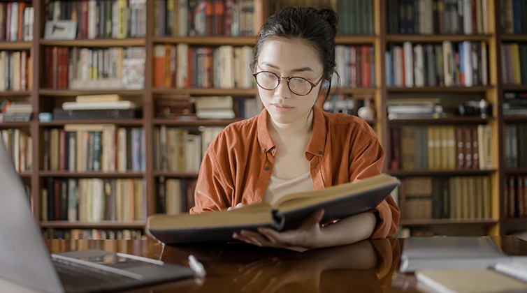 Woman sitting in library reading a book