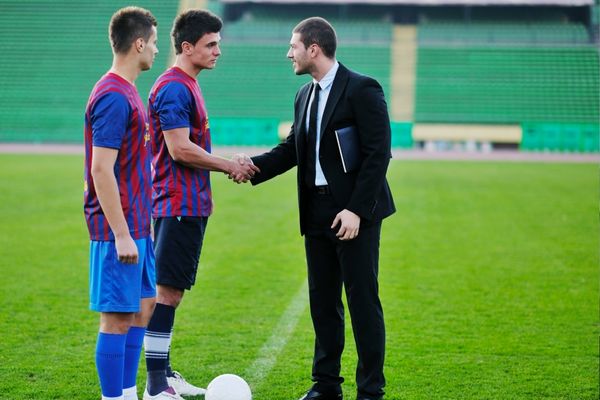 sports management professional shaking hands with soccer player