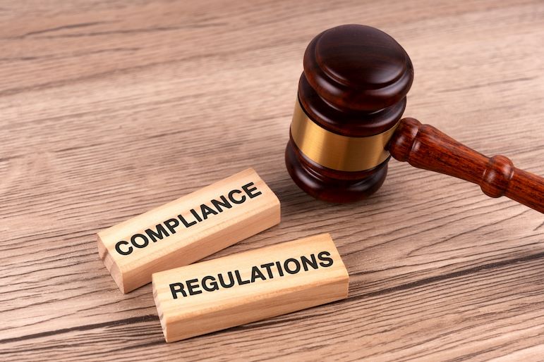 legal compliance vs. regulatory compliance written on wooden blocks near gavel