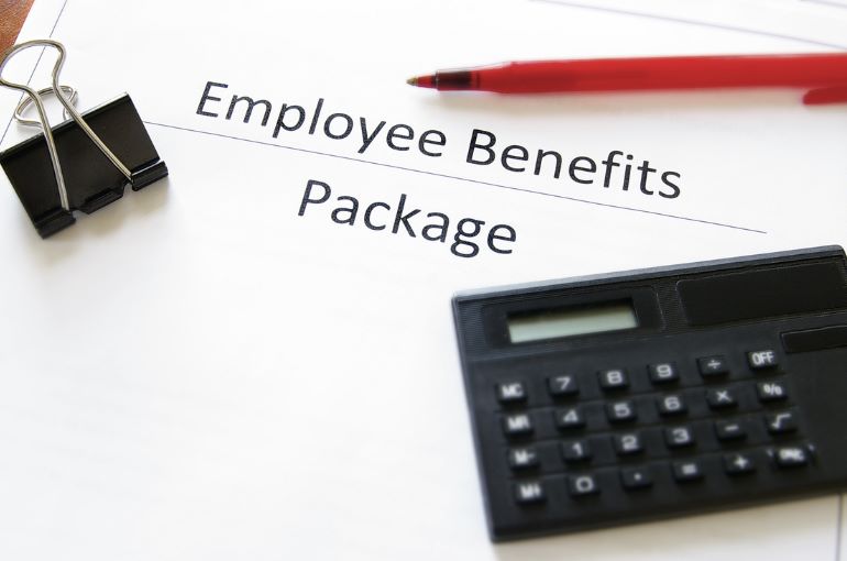 Employee benefits package document with pen, calculator, and binder clip.